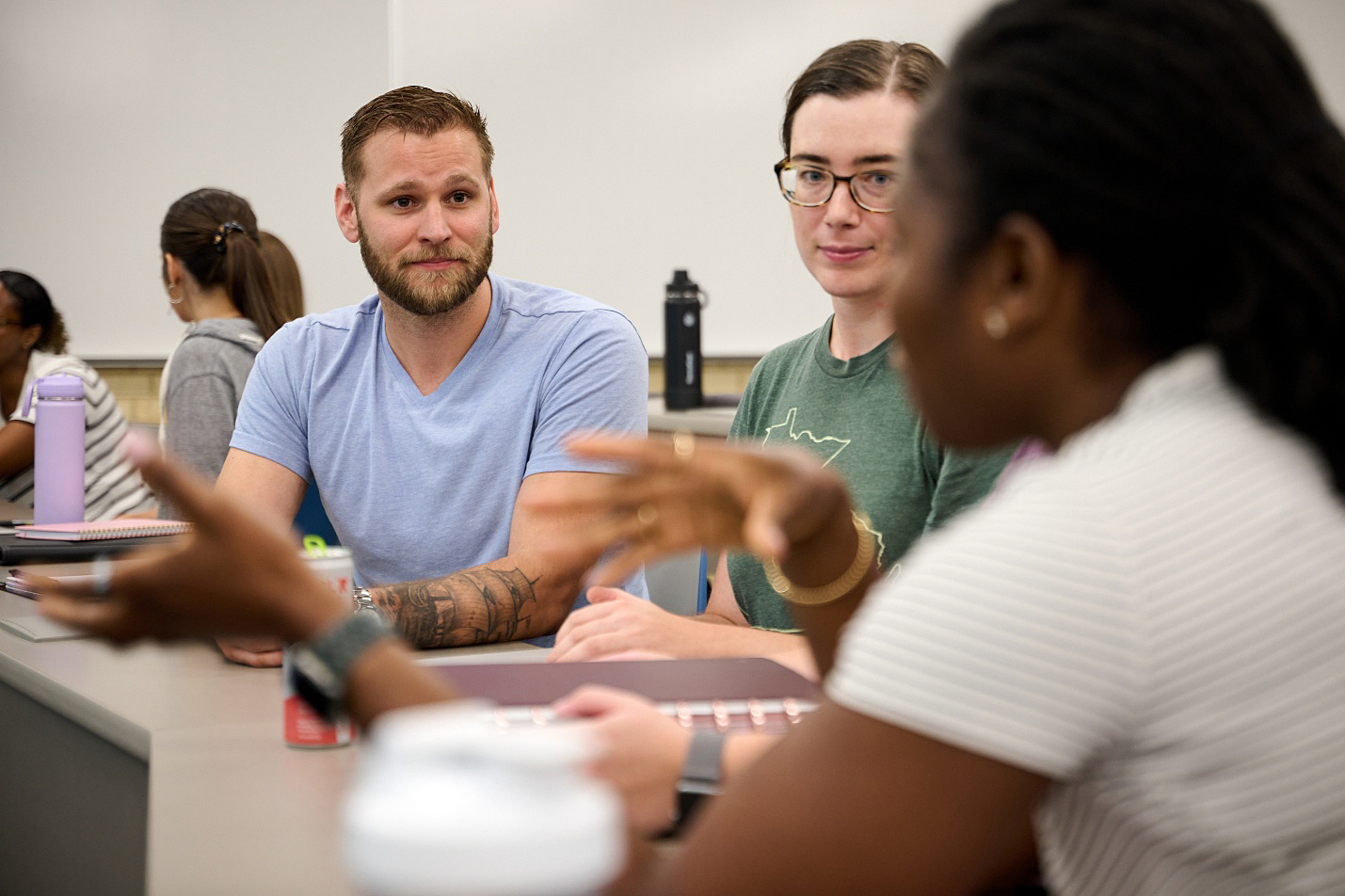 Three people in classroom conversing