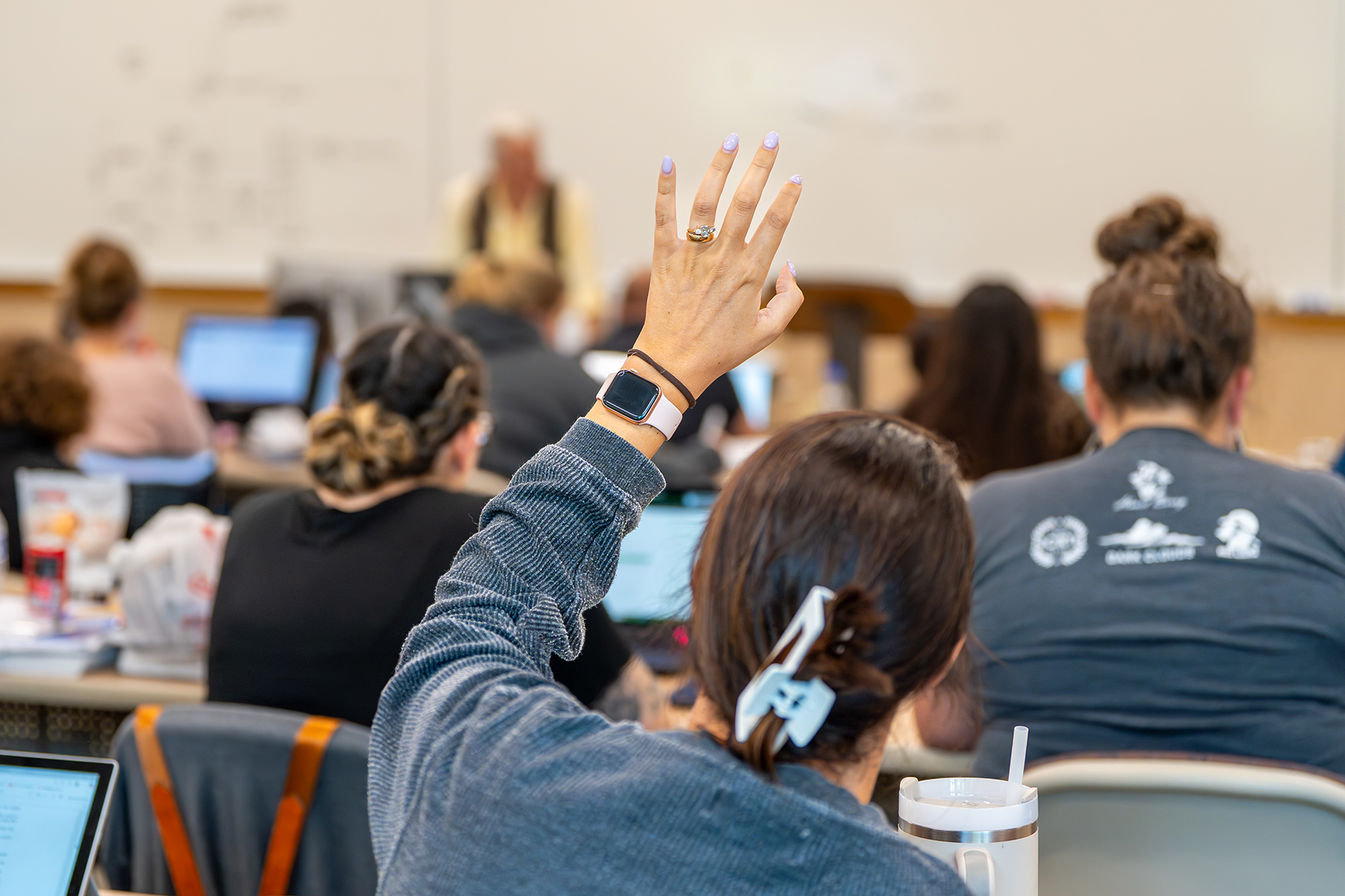 woman in classroom raising hand